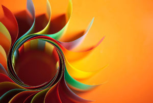multiple coloured papers fanned out in a sun shape on an orange background